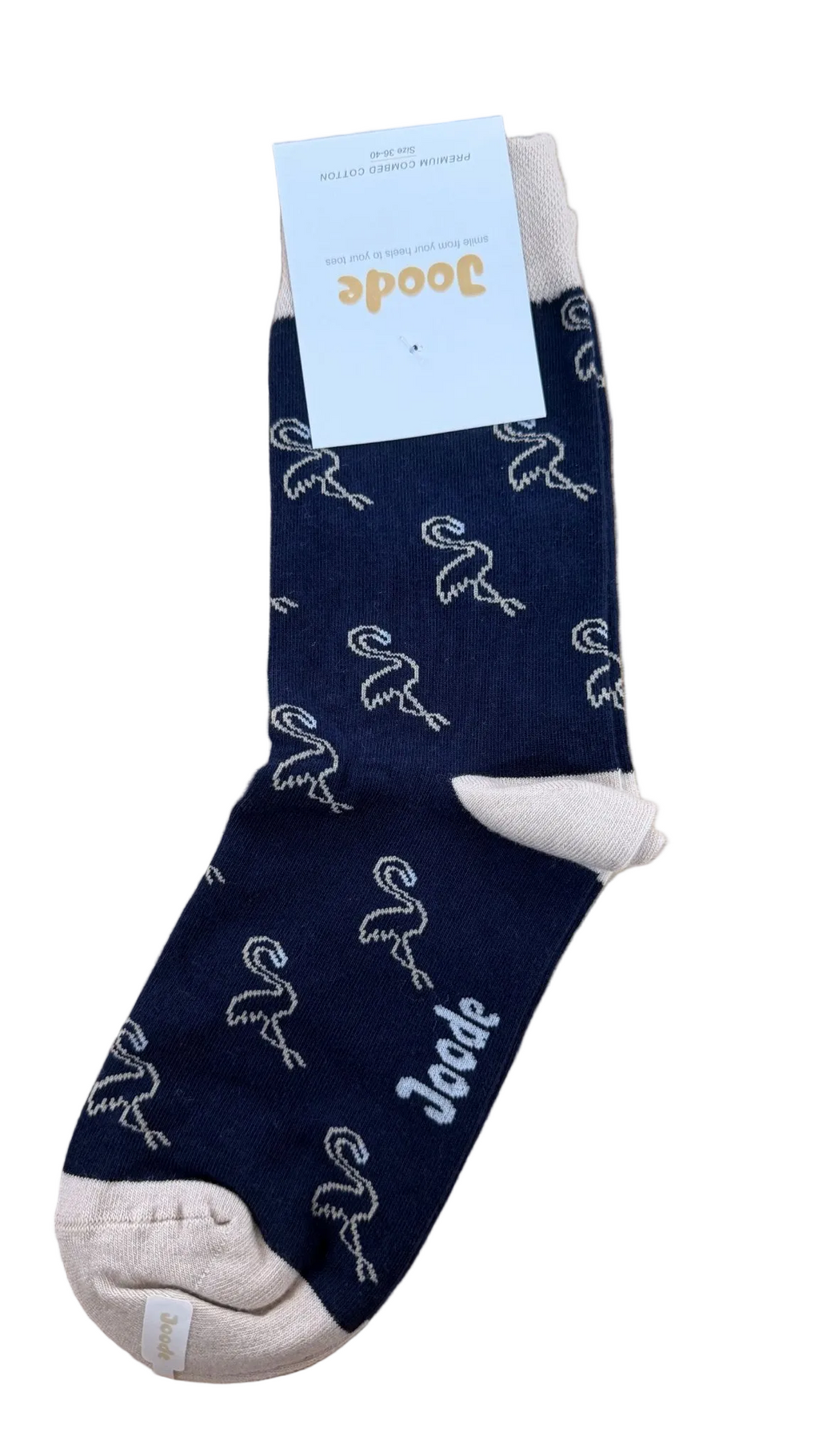 A single navy blue sock with a white flamingo pattern and a white cuff, shown on a light wood background with a white paper tag attached. The brand name 'Joode' is visible on the tag and printed on the sock.