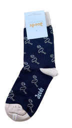 A single navy blue sock with a white flamingo pattern and a white cuff, shown on a light wood background with a white paper tag attached. The brand name 'Joode' is visible on the tag and printed on the sock.