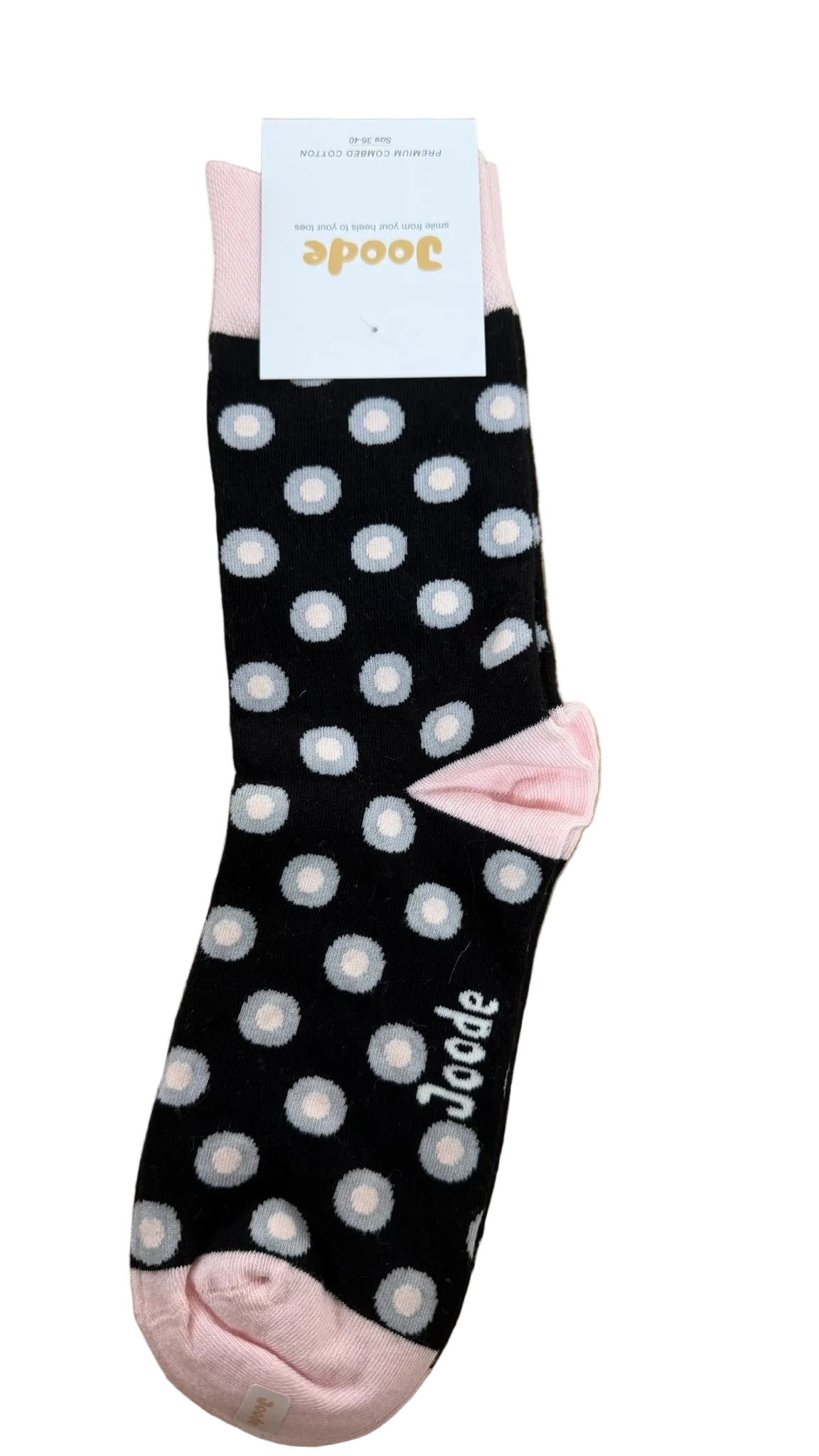 A single black sock with white polka dots, pink toe and heel, and a white paper tag attached, placed on a light wood floor. The brand name 'Jocode' is visible on the tag and printed on the sock.
