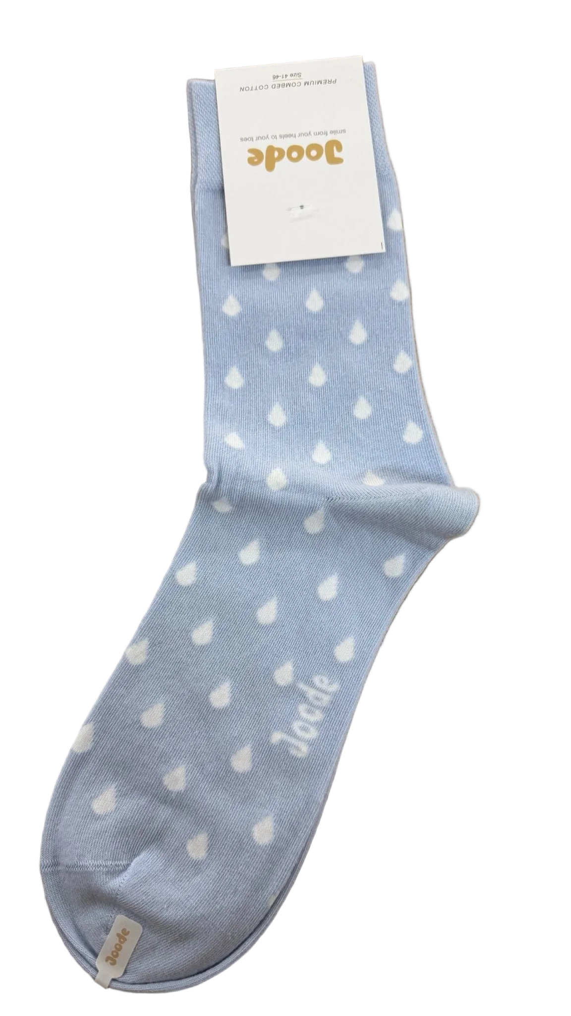 A single light blue sock with a white teardrop pattern and the Joode brand name printed near the toe, resting on a light brown wooden surface with its white paper tag attached.