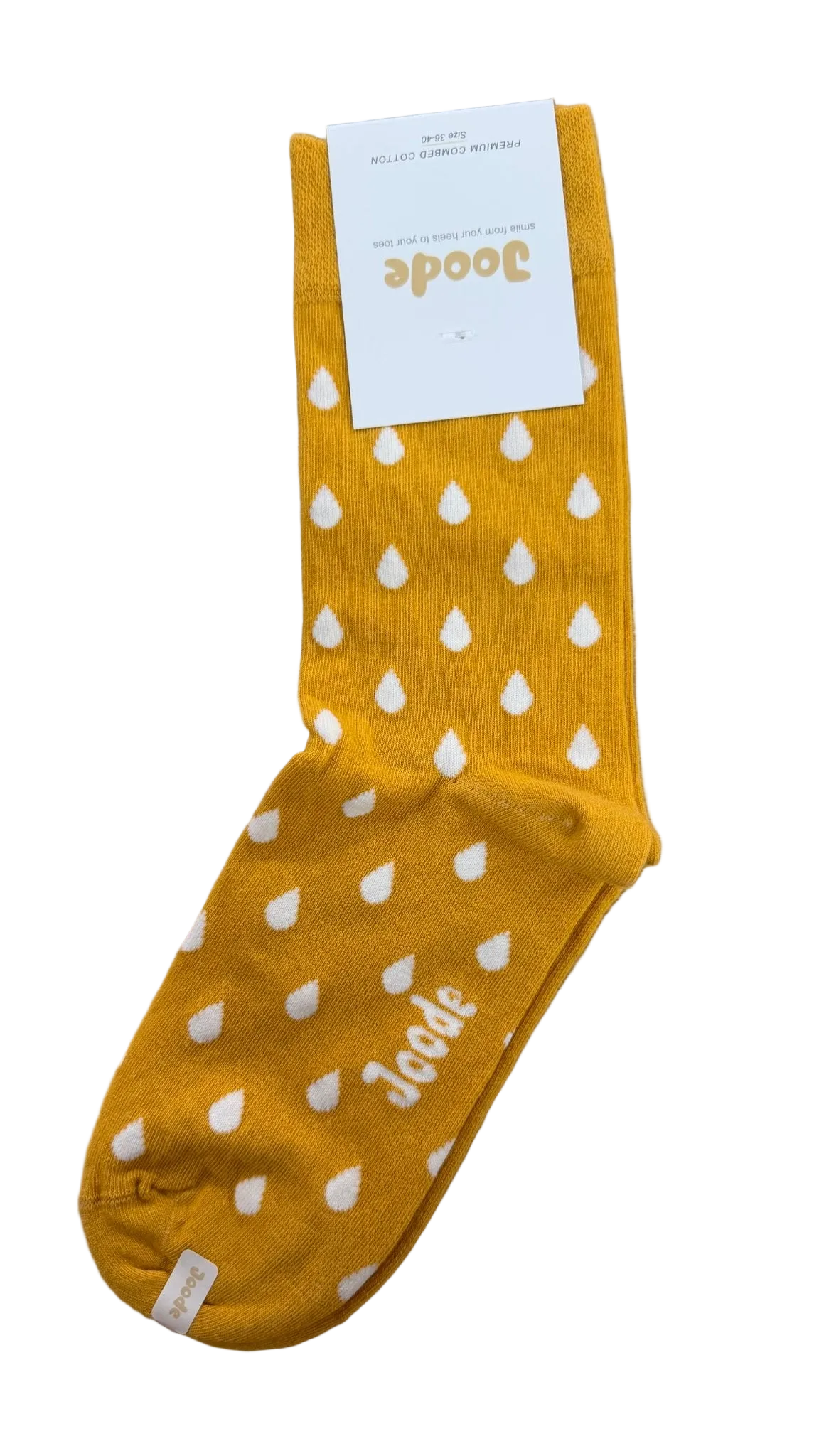 A single mustard yellow sock with white teardrop patterns and the brand name 'Joode' printed near the foot, resting on a light brown wooden surface with its white paper tag attached.
