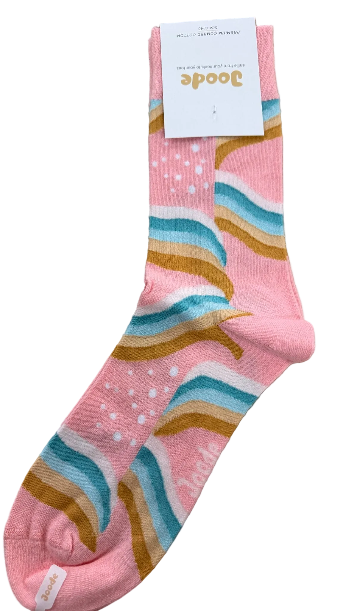 A single pink crew sock with a pastel rainbow stripe pattern in blue, teal, mustard, and brown, featuring white polka dots. A white paper tag with the brand name 'Boodee' is attached at the top, and the sock is laid flat on a light brown wooden surface.