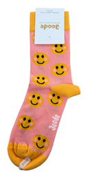 A single pink crew sock with a yellow toe, heel, and cuff, decorated with a repeating pattern of yellow smiley faces. The brand name 'Joode' is printed in white script near the foot, and the product is displayed on a light wood background with its retail tag attached.