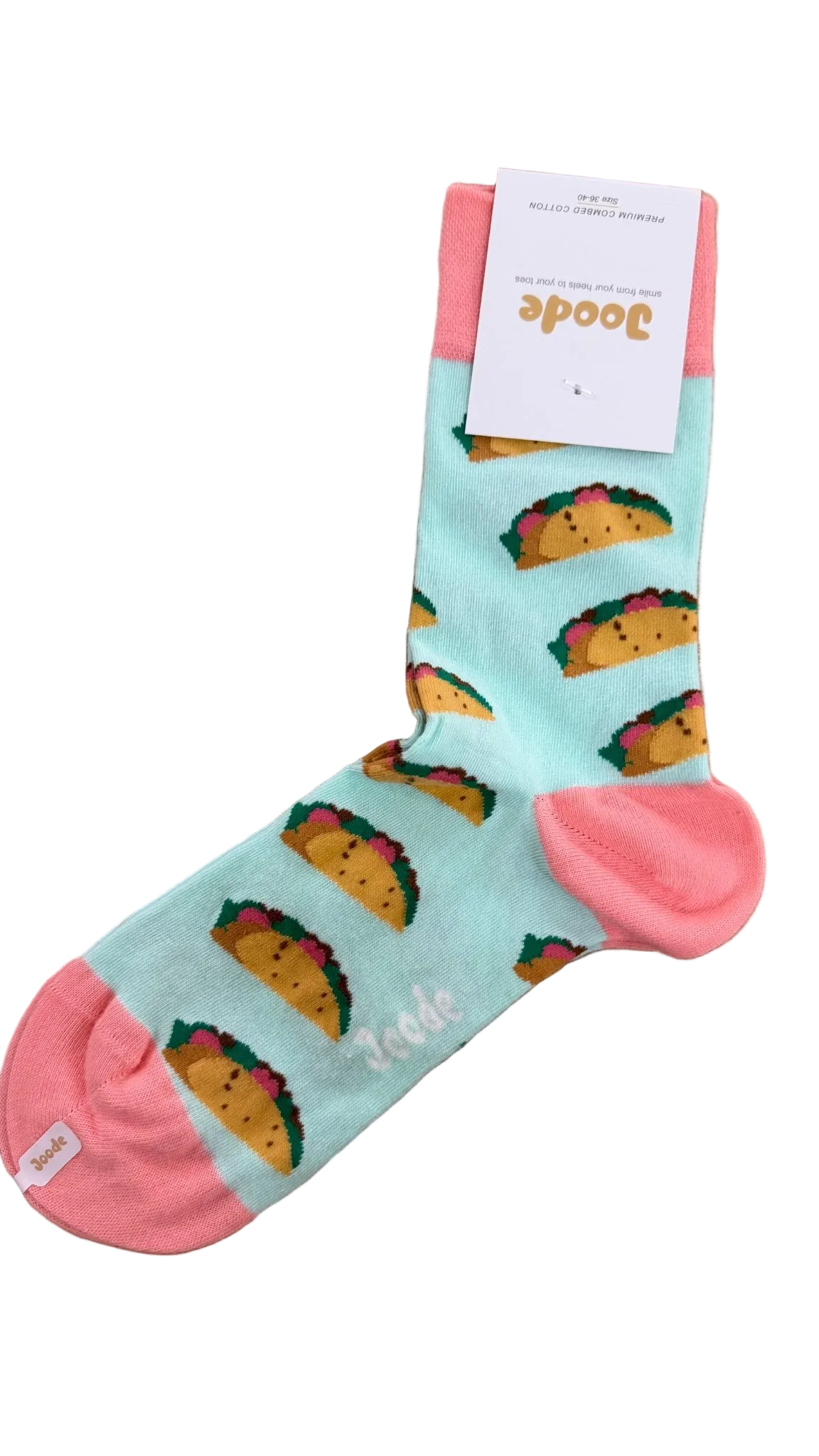 A single light blue sock with a repeating taco print and pink toe/heel/cuff, laid flat on a wooden surface with a white paper tag attached.