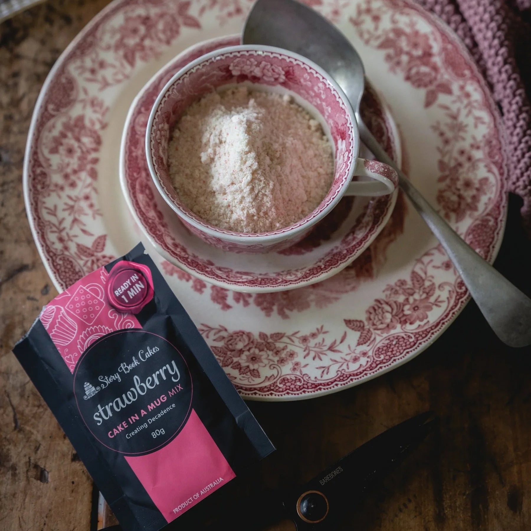 Cup of coffee with a strawberry flavored packet on a patterned saucer