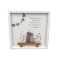Decorative wall art with two stone figures on a bench, flowers, and heart decorations.