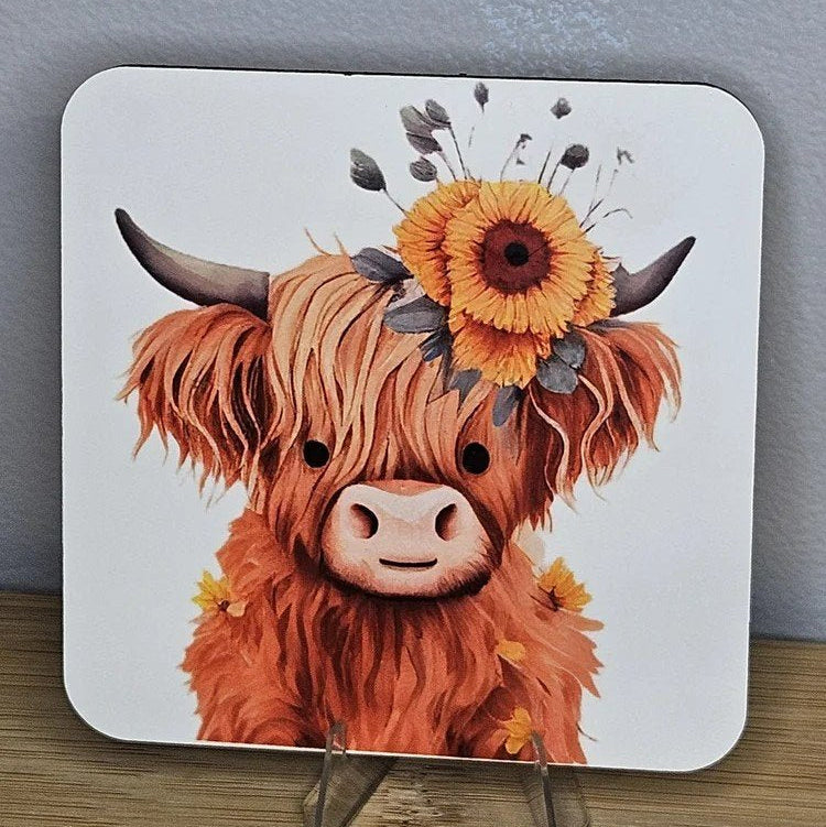 Coaster with a highland cow design featuring flowers on a stand against a gray background