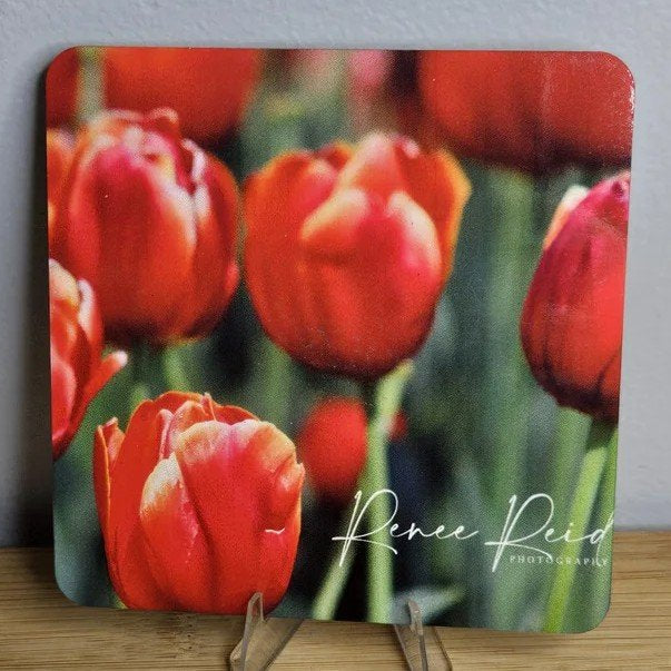 Decorative Coaster with red tulips design and 'Renee Reid' branding on a wooden stand.
