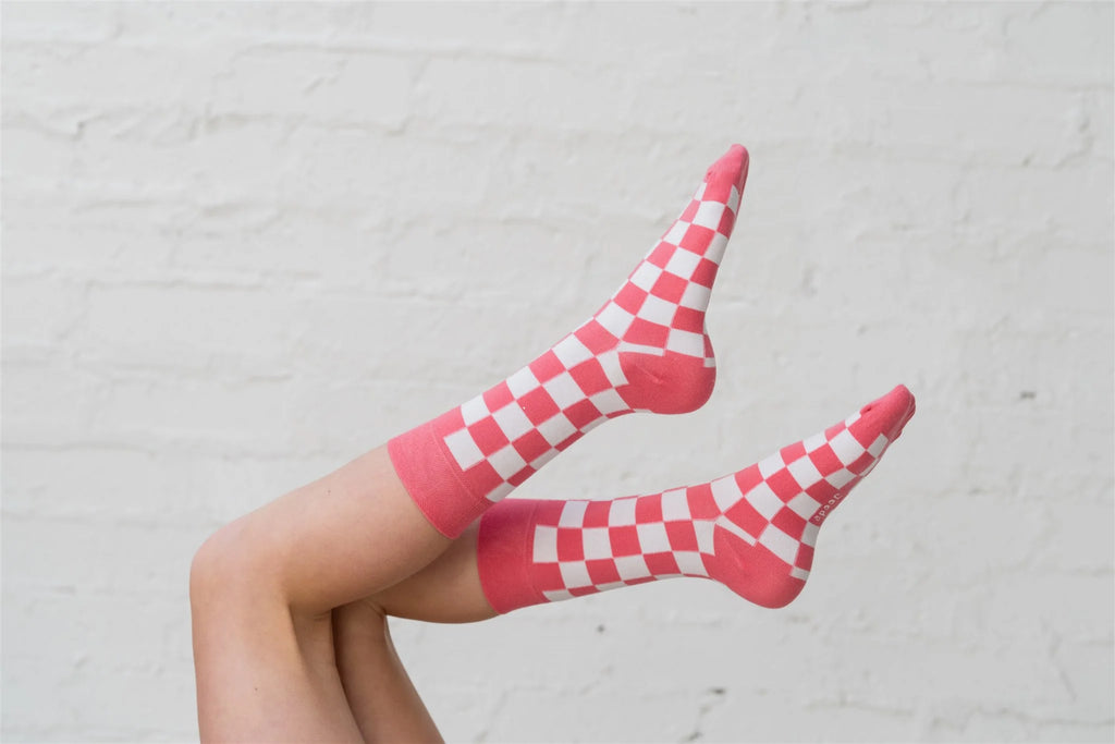 Red and white checkered socks worn by a person against a light gray background
