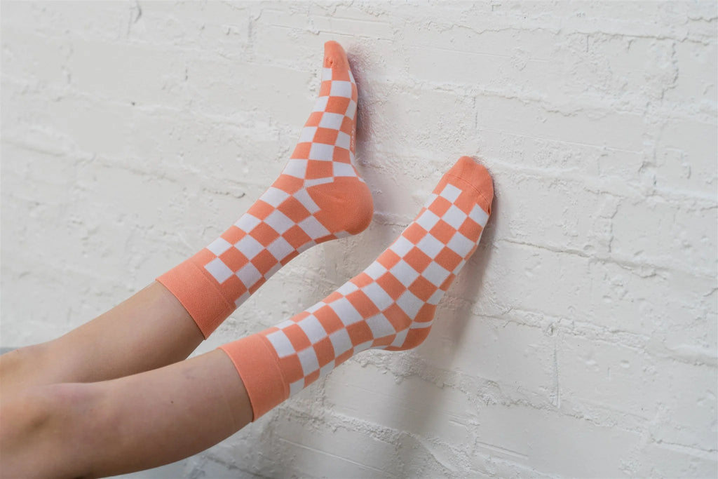 Orange and white checkered socks on a light gray floor.