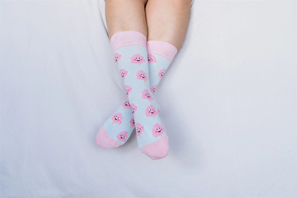Light blue socks with pink cartoon characters worn by a person on a light gray background