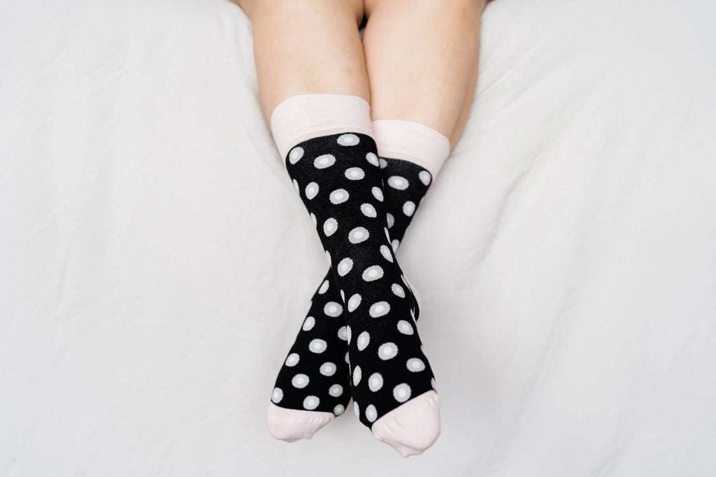 Person wearing black polka dot socks on a light gray background