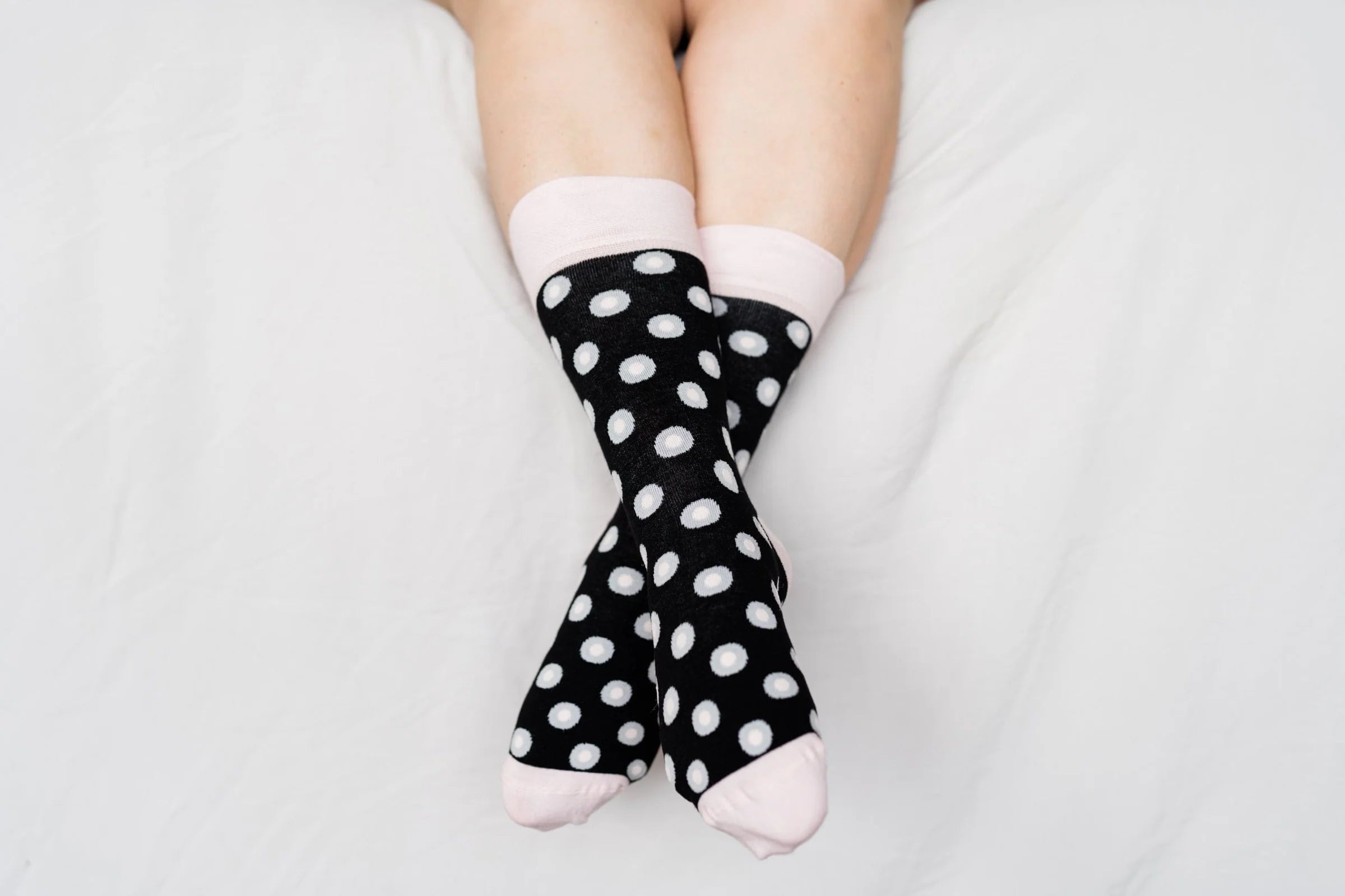 Person wearing black polka dot socks on a light gray background
