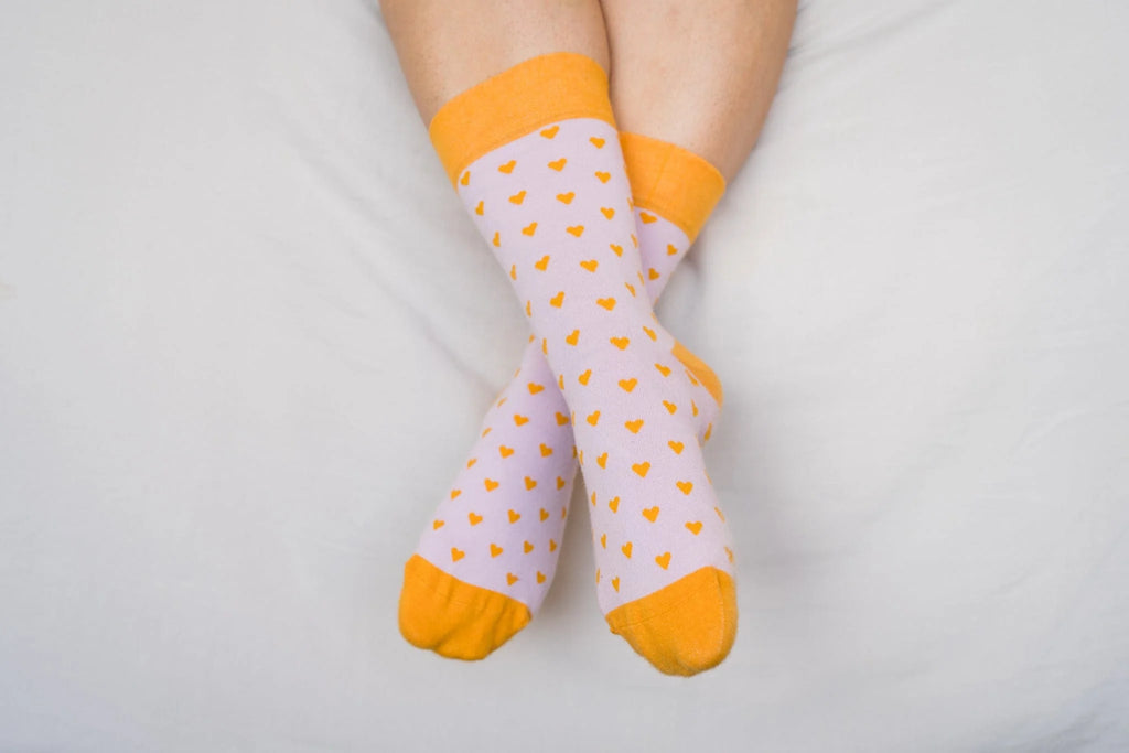 White socks with orange hearts and cuffs on a white background