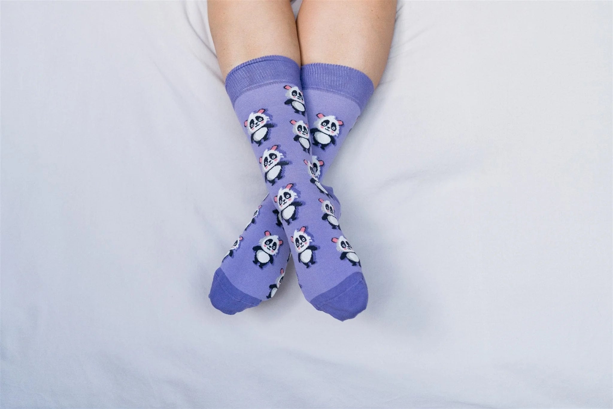 Purple socks with panda design worn by a person on a light gray background