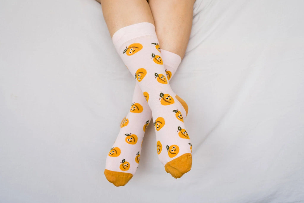 White socks with orange patterns worn by a person on a light gray background