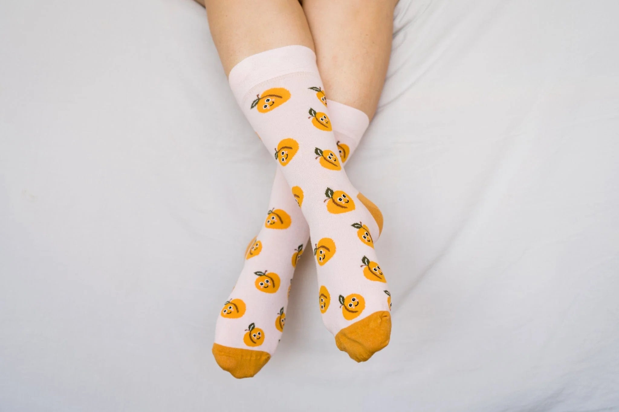 White socks with orange patterns worn by a person on a light gray background