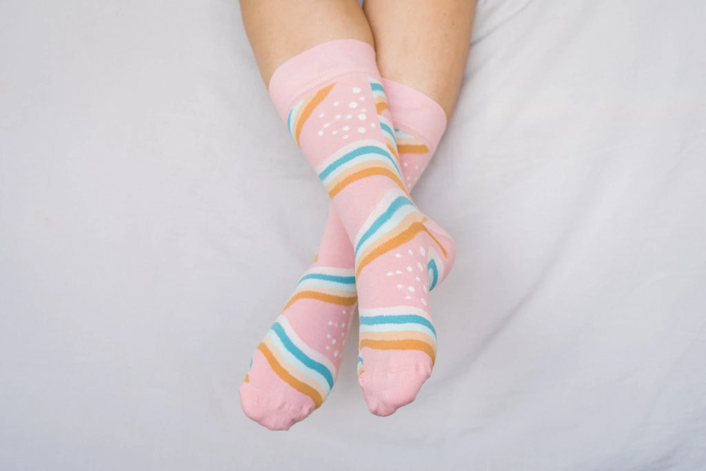 Pink socks with colorful stripes on a light gray background
