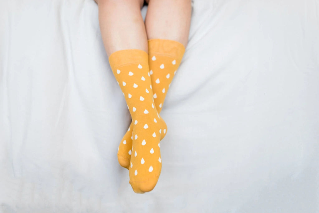Yellow socks with white polka dots on a light gray background